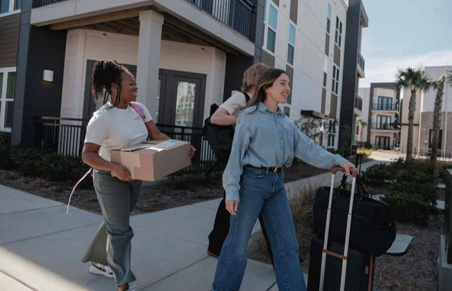Deux jeunes intervenantes portant des cartons devant un local
