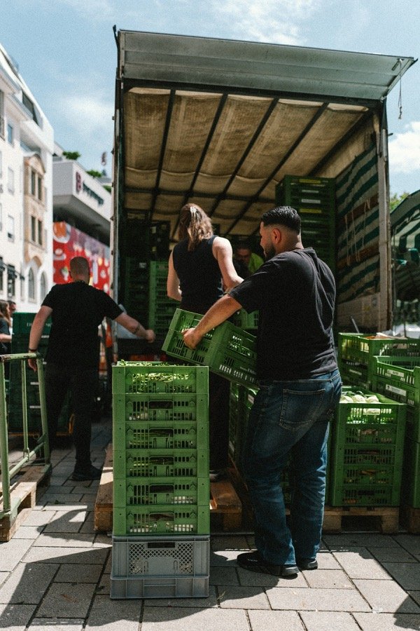 Trois jeunes déchargeant des caisses à l'arrière d'un camion